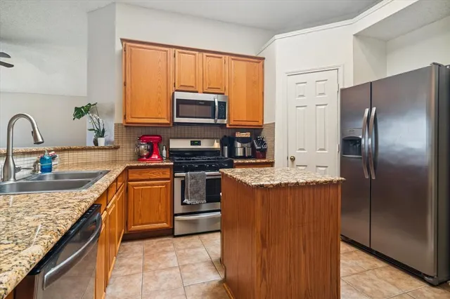 a kitchen with stainless steel appliances granite countertop a refrigerator and a stove top oven