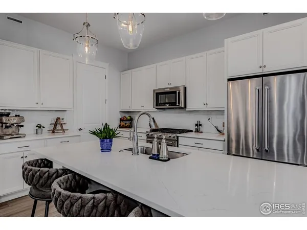 a kitchen with refrigerator a sink and chairs