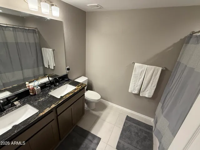 a bathroom with a granite countertop sink toilet and mirror