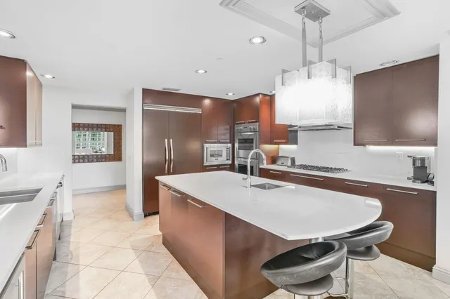 a kitchen with stainless steel appliances a dining table chairs sink and wooden floor