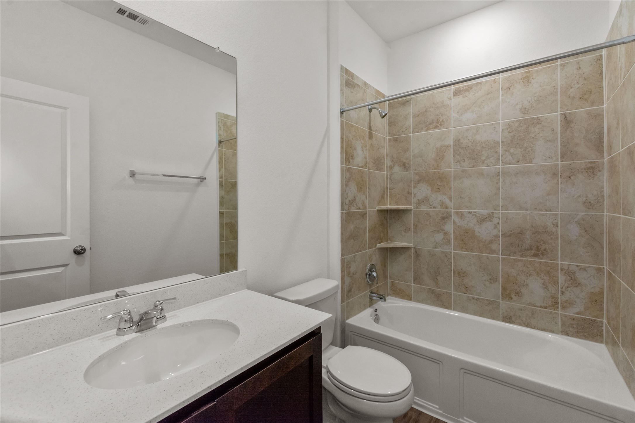 1108 Mallow Road Leander, TX 78641 - Photo 16 of 30 A classic bathroom layout includes a stone-patterned tiled tub surround and clean white vanity countertop.