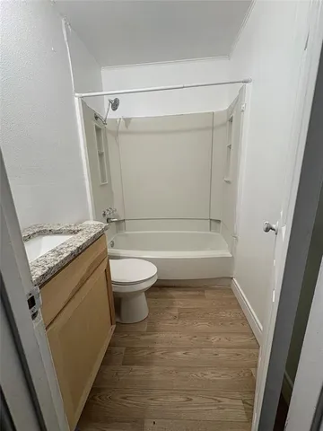 a bathroom with a granite countertop bathtub shower sink vanity and toilet