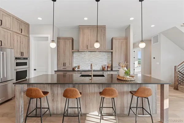 a kitchen with stainless steel appliances granite countertop a sink a stove and a wooden floor