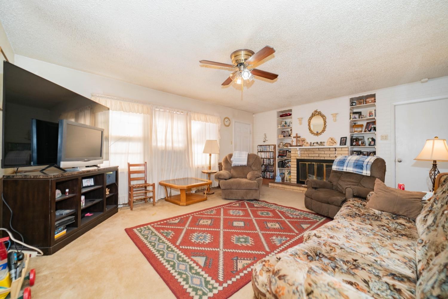 4811 43rd Street Lubbock, TX 79414 - Photo 5 of 20 a living room with furniture a flat screen tv and a fireplace