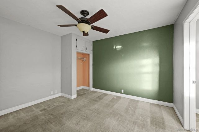 an empty room with a ceiling fan and window