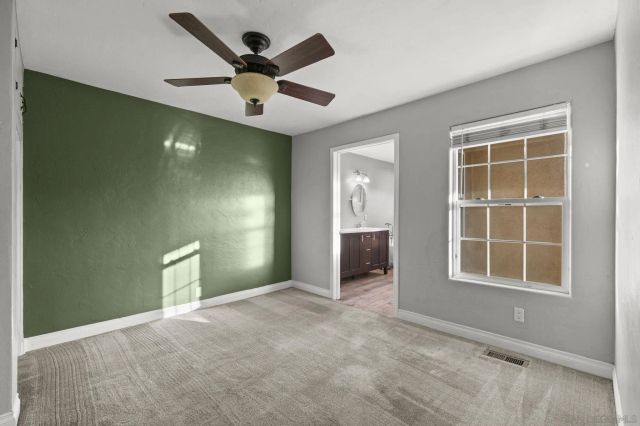 an empty room with ceiling fan and windows