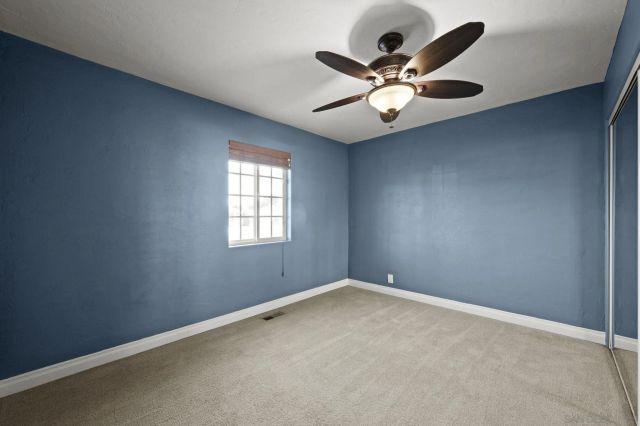 an empty room with a window and a fan