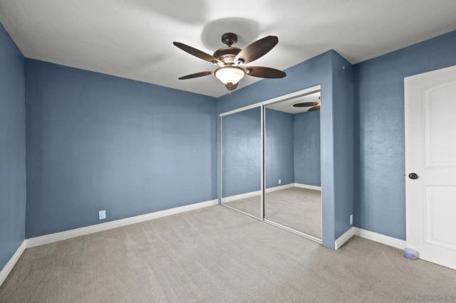 an empty room with closet and a ceiling fan