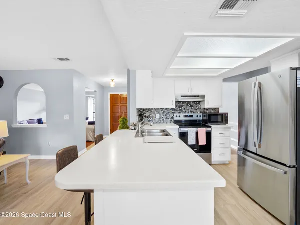 a large kitchen with a refrigerator a sink a stove top oven and cabinets