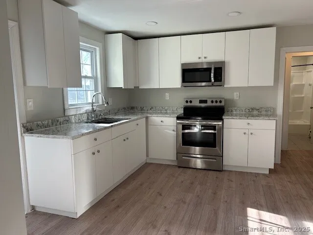 a kitchen with granite countertop white cabinets and stainless steel appliances