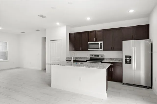 a kitchen with stainless steel appliances granite countertop a refrigerator a stove a microwave oven a sink with dishwasher and refrigerator