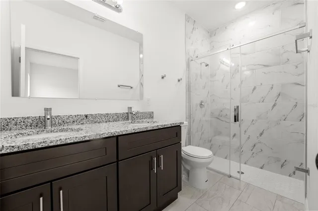 a bathroom with a granite countertop sink toilet and shower