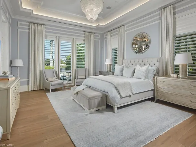 a spacious bedroom with a bed a mirror and a large window