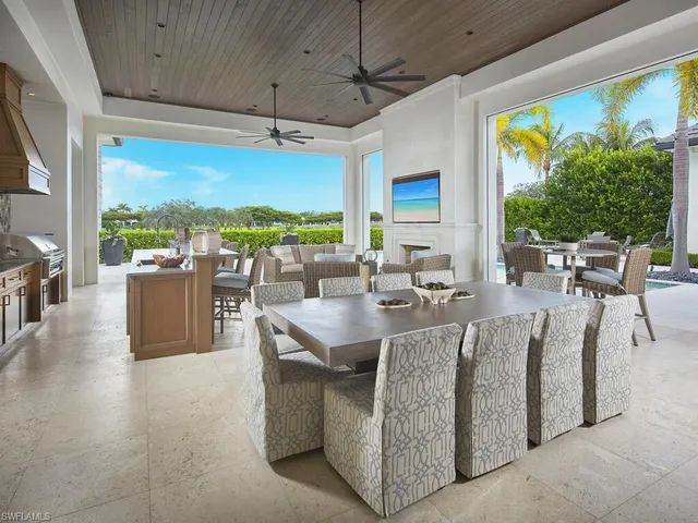 a living room with couches a flat tv screen and a floor to ceiling window with outer view