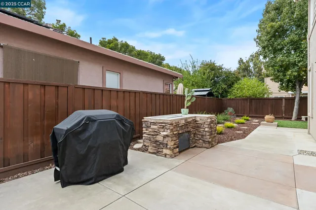 a view of a backyard with a barbeque and wooden fence