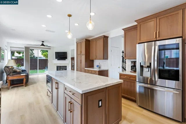 a kitchen with stainless steel appliances granite countertop a refrigerator a oven a stove and a sink with wooden floor