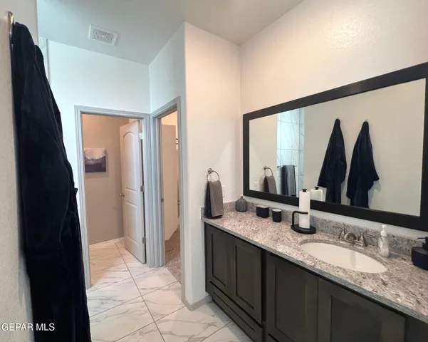 a bathroom with a granite countertop double vanity sink and a mirror