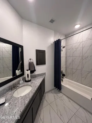 a bathroom with a granite countertop sink a mirror and shower