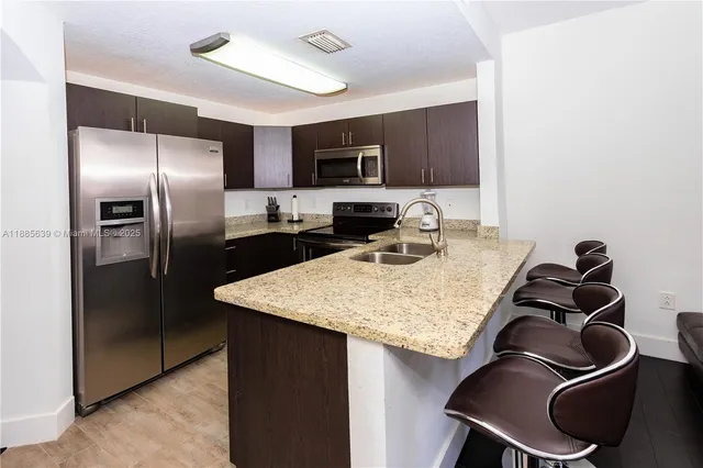 a kitchen with stainless steel appliances granite countertop a sink stove and refrigerator