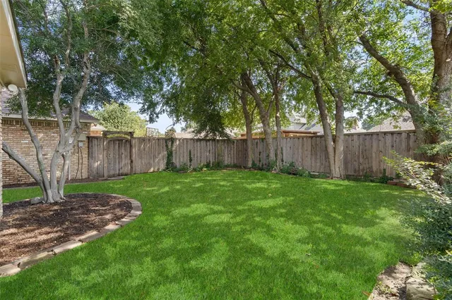 a view of a backyard with large trees and wooden fence