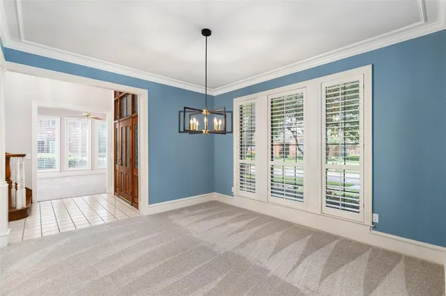 a view of an empty room with window and chandelier
