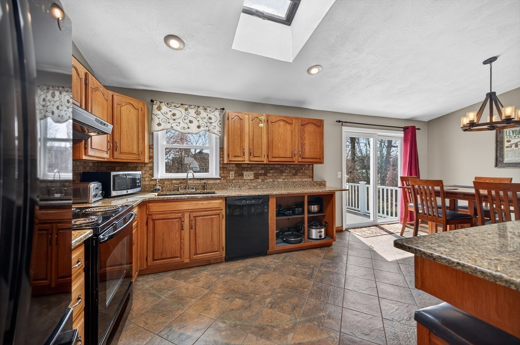 1079 Langley Street Fall River, MA 02720 - Photo 13 of 40 a kitchen with stainless steel appliances granite countertop a stove top oven a sink dishwasher a dining table and chairs with wooden floor