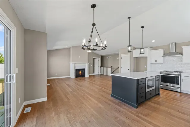 a living room with stainless steel appliances granite countertop a sink a fireplace with wooden floor