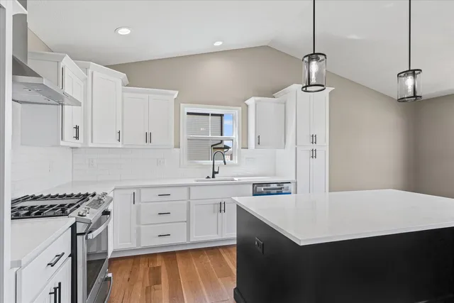 a kitchen with a sink a stove a refrigerator and white cabinets