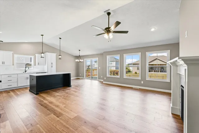 a view of an empty room with wooden floor and a kitchen