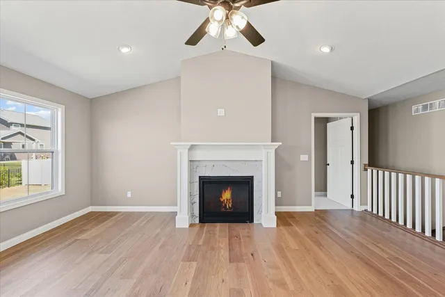 a view of an empty room with wooden floor fireplace and a window