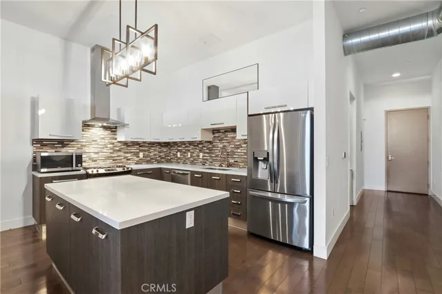 a kitchen with kitchen island a counter top space stainless steel appliances and wooden floor