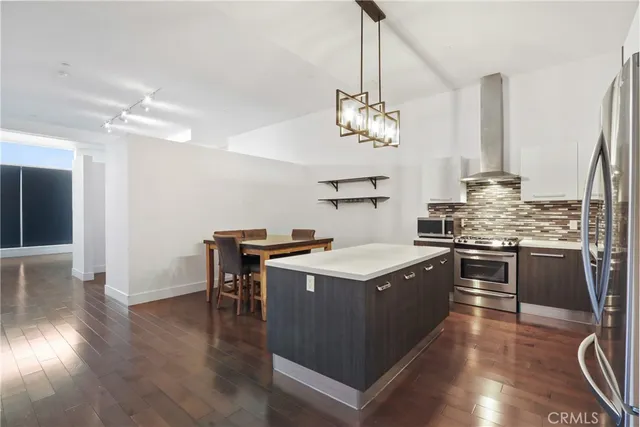 a kitchen with a center island wooden floor and stainless steel appliances