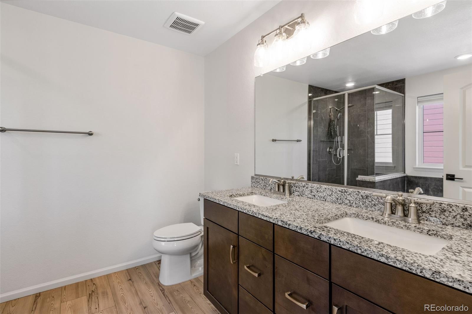 306 Rodden Drive Erie, CO 80516 - Photo 19 of 49 a bathroom with a granite countertop sink a toilet and a mirror