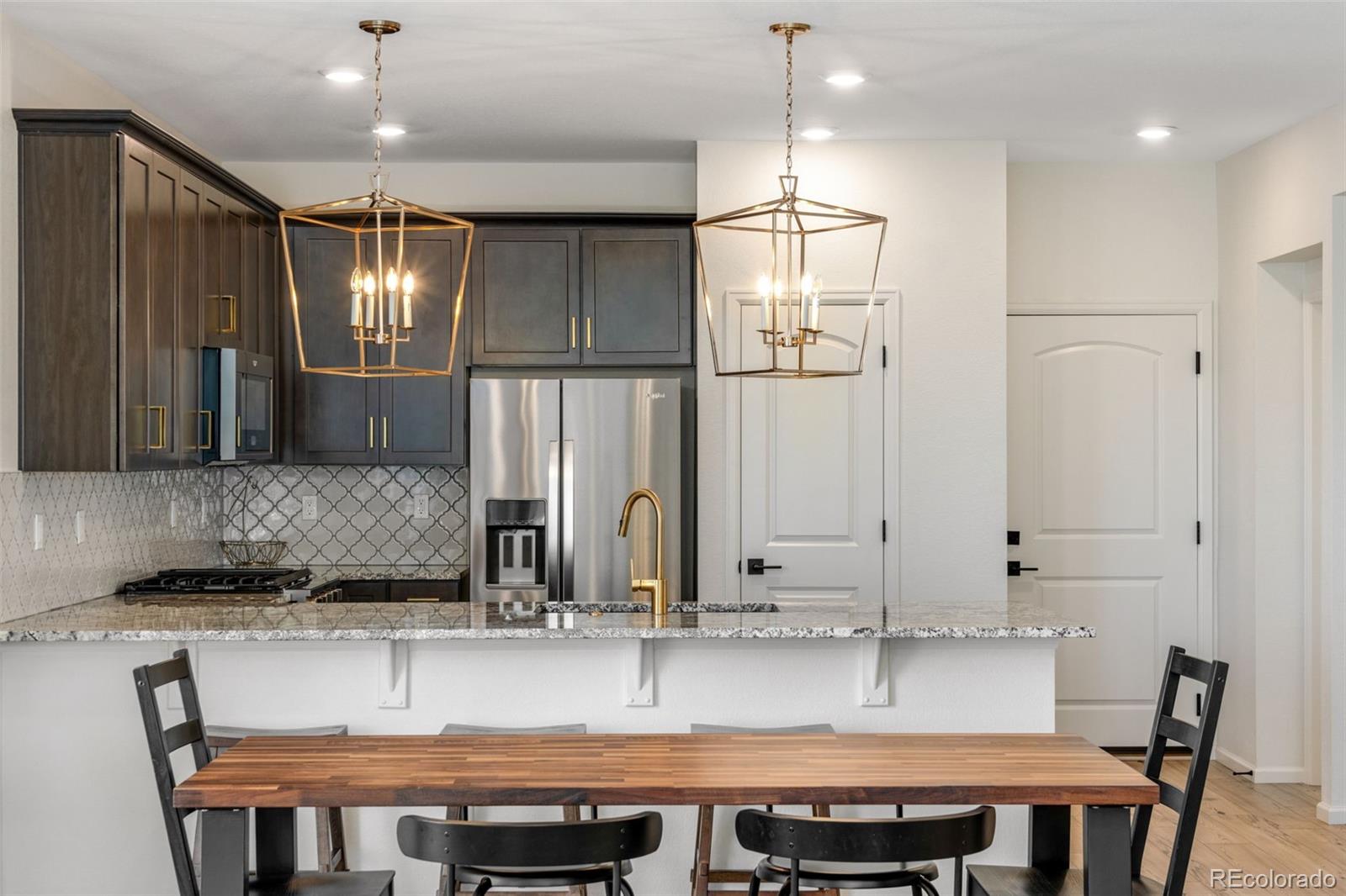 306 Rodden Drive Erie, CO 80516 - Photo 10 of 49 a kitchen with kitchen island granite countertop a table chairs sink and cabinets