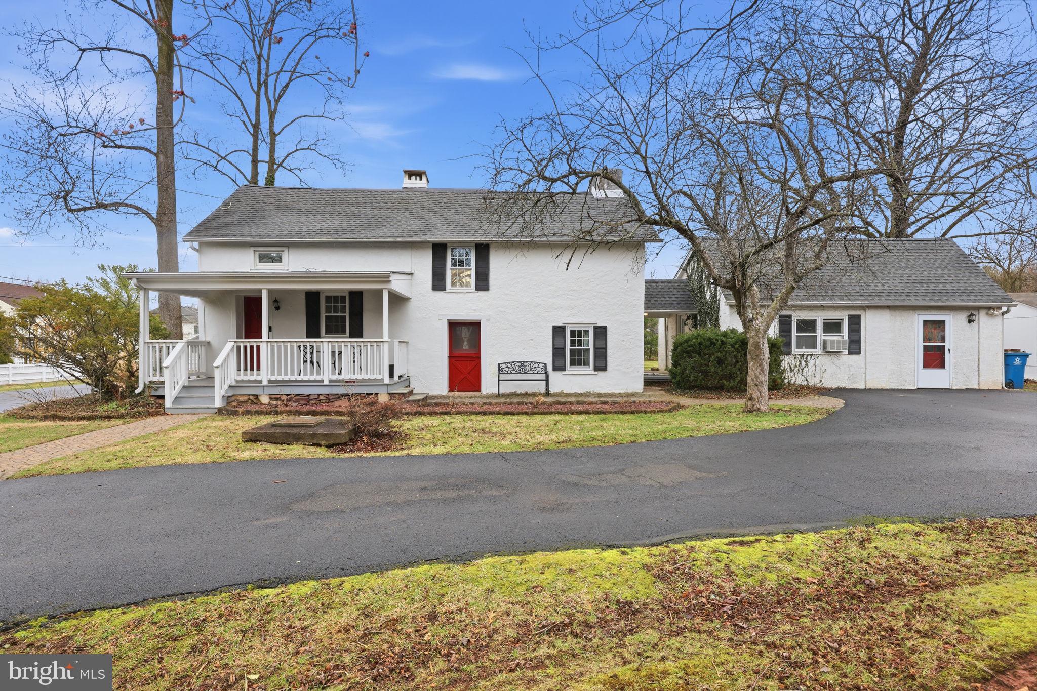 a view of a white house with a large tree and wooden fence