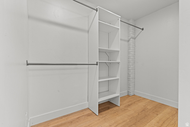 2101 West 3900th Street South Roy, UT 84067 - Photo 14 of 36 Walk-in closet featuring built-in white shelving, multiple hanging rods, light wood-finish flooring, and white painted brick accents