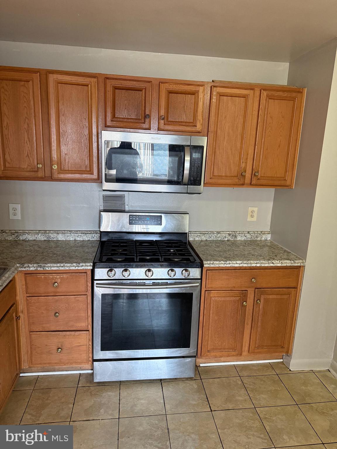 8830 Piney Branch Road Silver Spring, MD 20903 - Photo 11 of 15 a kitchen with granite countertop a stove top oven microwave and cabinets