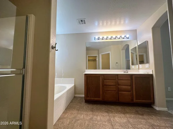 a spacious bathroom with a tub double sink and mirror