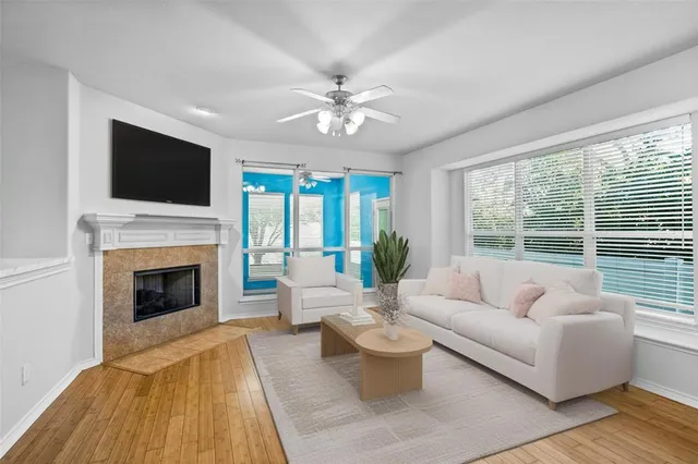 a view of an empty room with wooden floor fireplace and a window