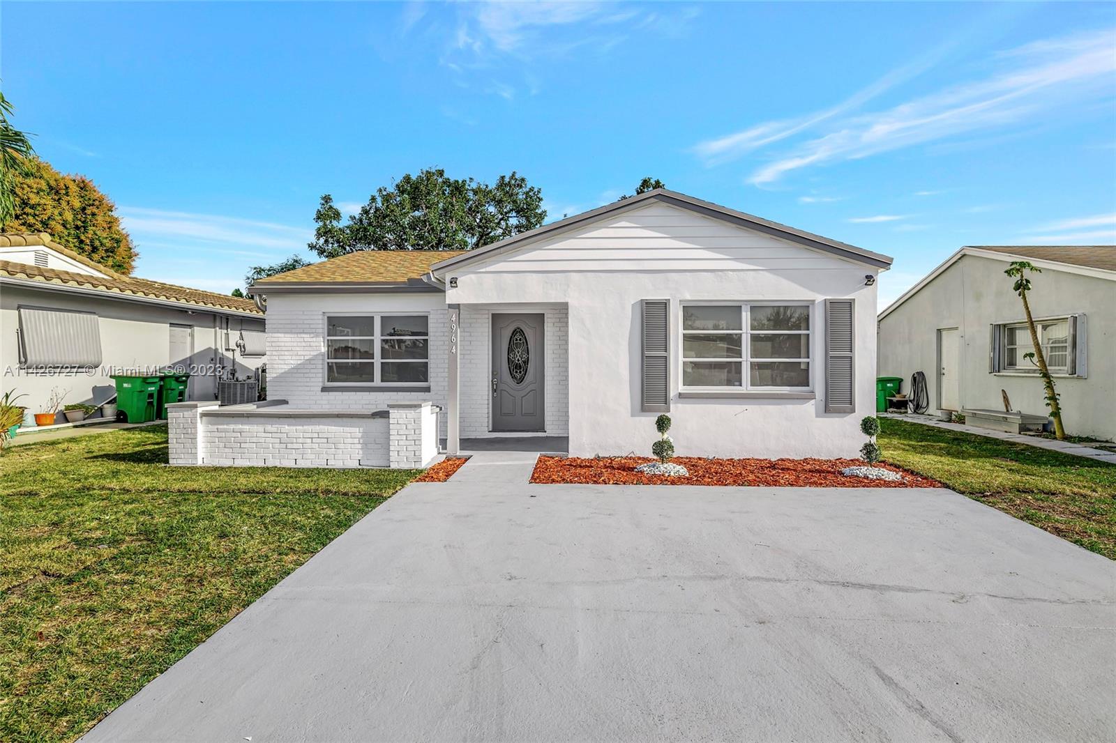 4964 Northwest 48th Way Tamarac, FL 33319 - Photo 1 of 16 a white house with a large yard plants and large tree