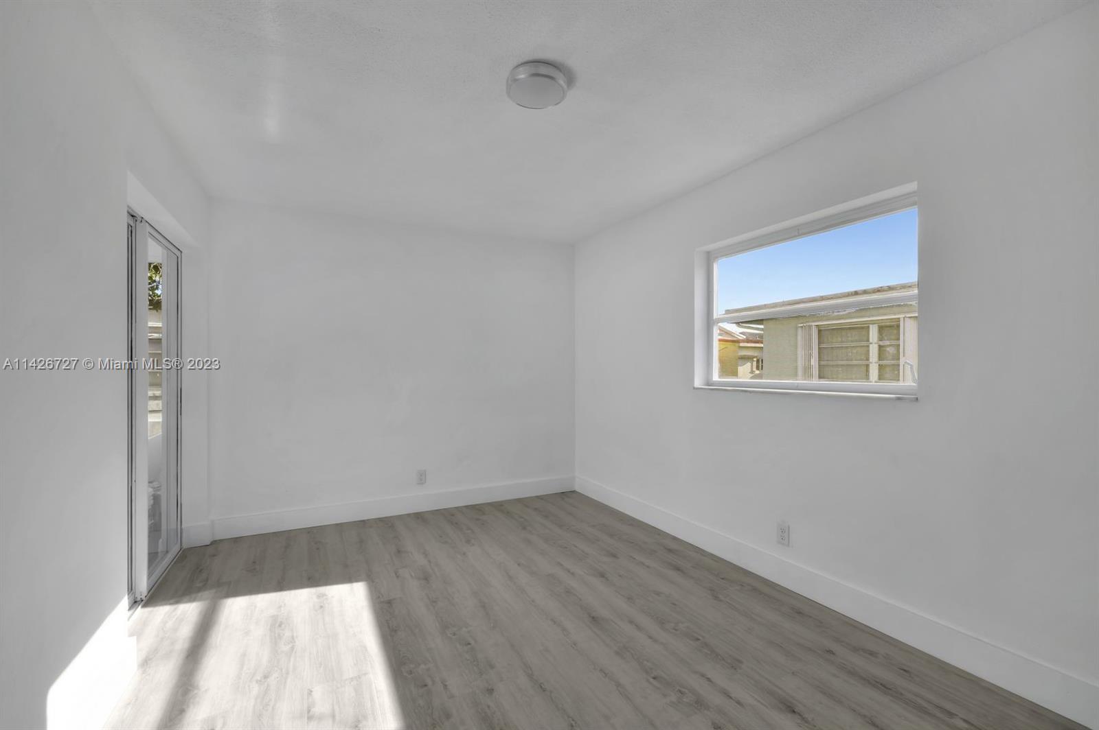 4964 Northwest 48th Way Tamarac, FL 33319 - Photo 11 of 16 an empty room with wooden floor and windows