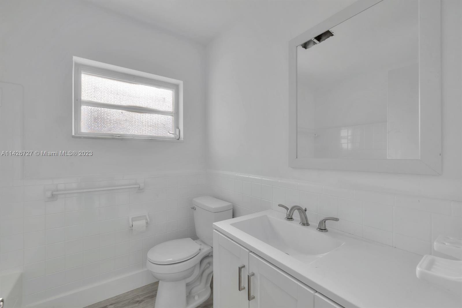 4964 Northwest 48th Way Tamarac, FL 33319 - Photo 3 of 16 a bathroom with a toilet sink vanity and mirror