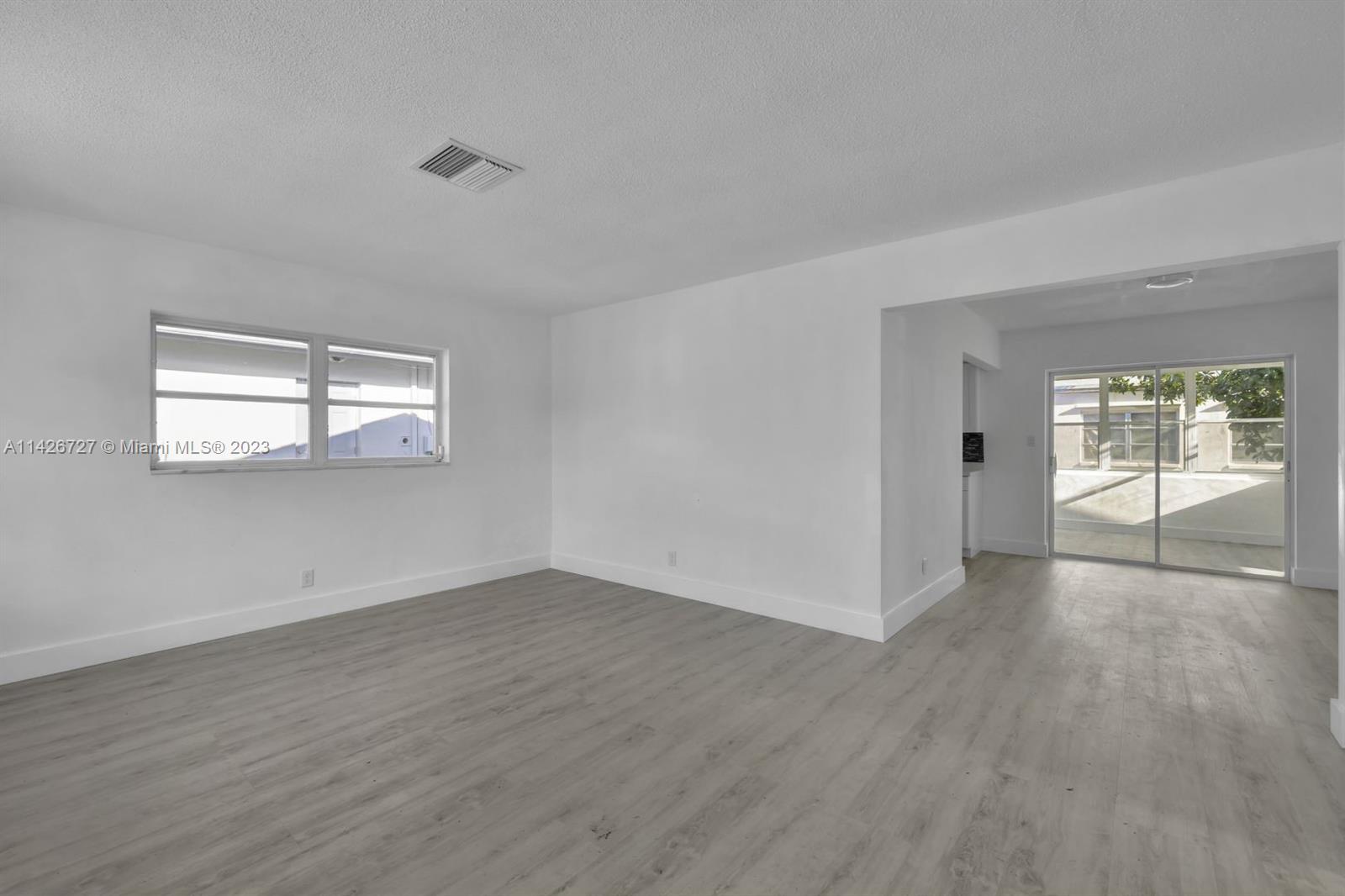 4964 Northwest 48th Way Tamarac, FL 33319 - Photo 9 of 16 an empty room with wooden floor and windows
