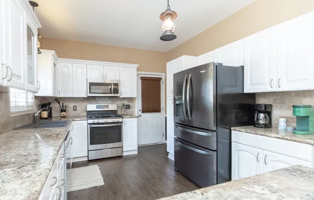 a kitchen with stainless steel appliances granite countertop a refrigerator a stove a sink and a microwave