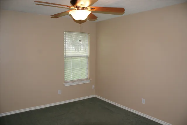 an empty room with a window and a fan