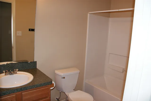 a bathroom with a granite countertop sink toilet and a mirror