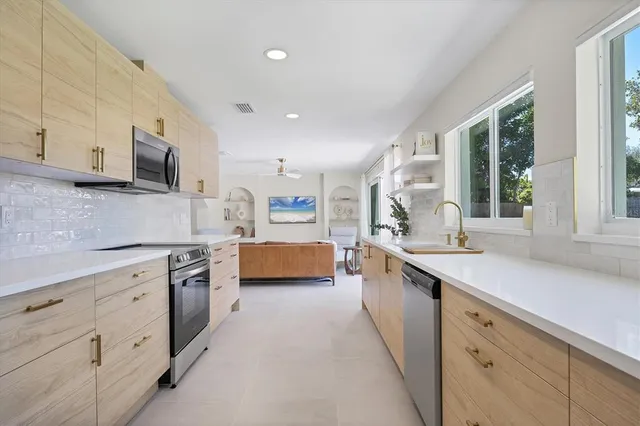 a large white kitchen with stainless steel appliances granite countertop a lot of counter space and a sink