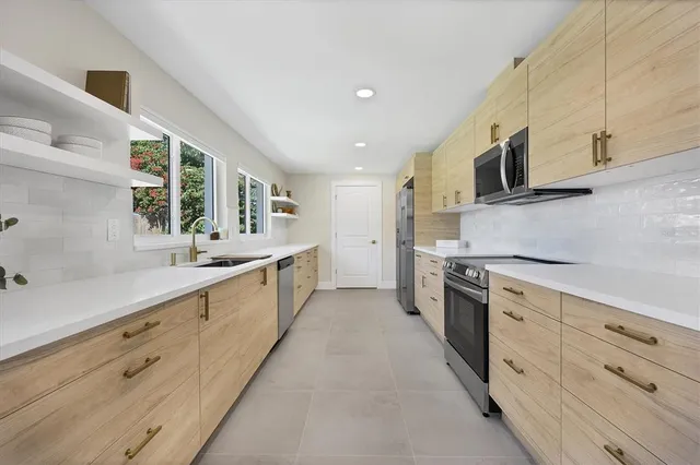 a large kitchen with stainless steel appliances lots of counter space sink and a window