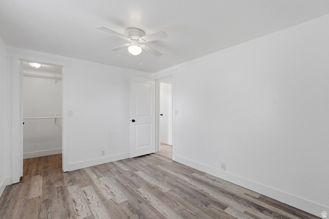 2875 North Hill Field Road, Unit 111 Layton, UT 84041 - Photo 21 of 30 Unfurnished bedroom with light wood-style flooring, a ceiling fan, and a walk in closet