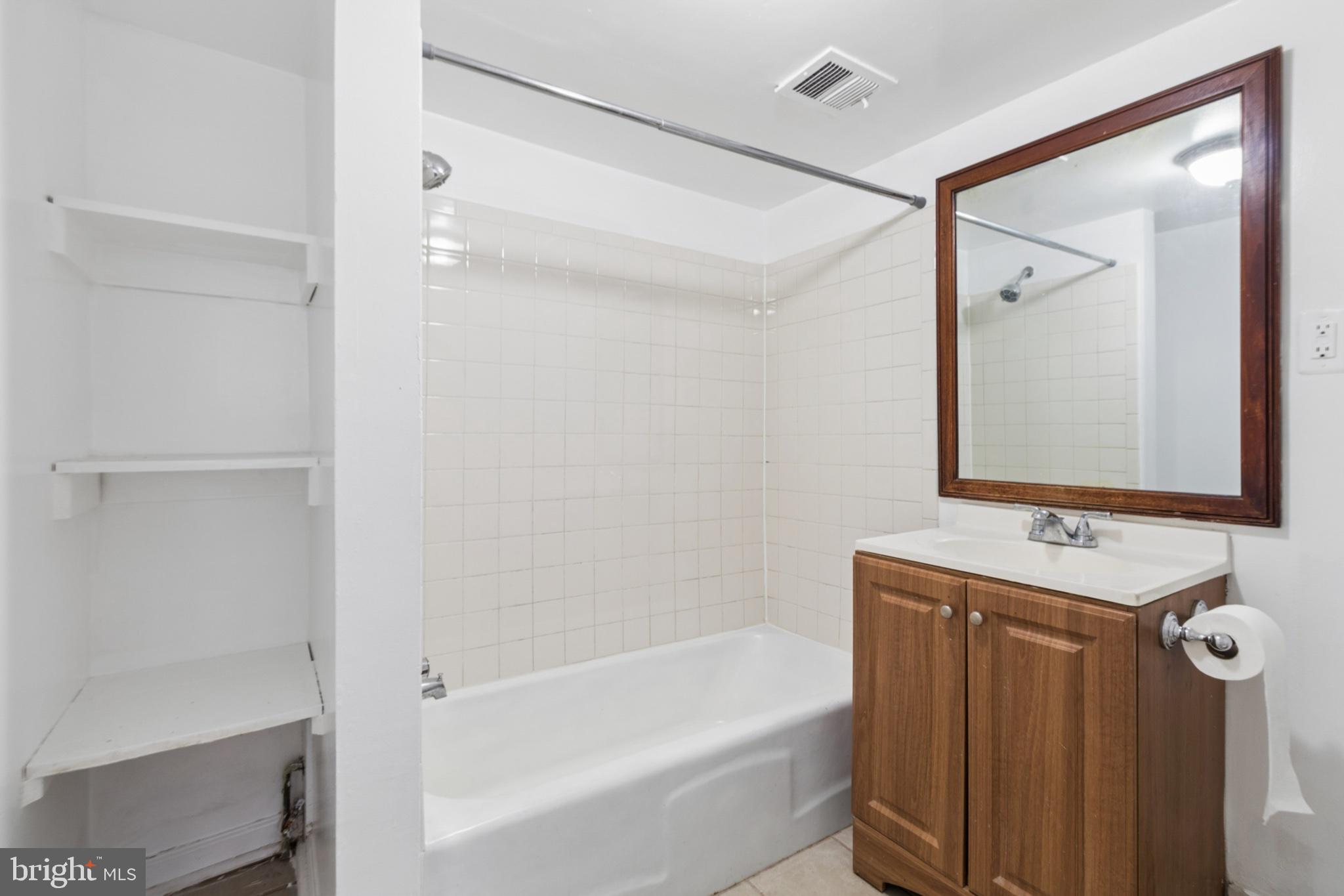 407 Lebaum Street Southeast, Unit 4 Washington, DC 20032 - Photo 8 of 18 a bathroom with a bathtub a shower a sink and a mirror